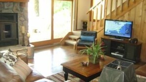 Una sala de estar con chimenea, televisor y escalera.