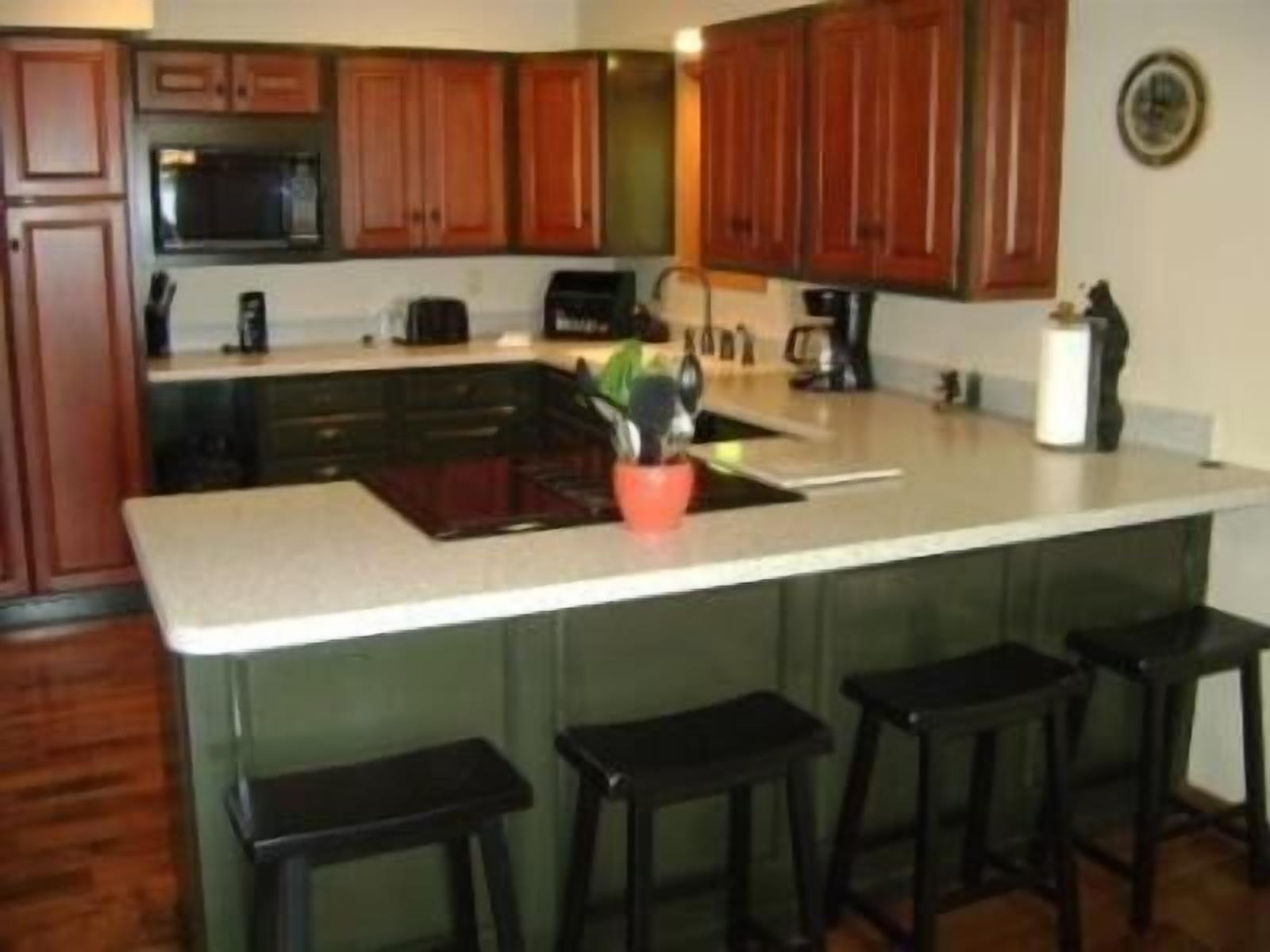 A kitchen with wooden cabinets, a microwave, a coffee maker, and a sink.