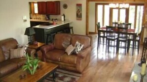 Un salón amplio con un sofá de cuero, una mesa de centro de madera y un comedor con mesa y sillas.
