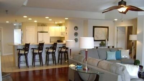 A living room with a sofa, a coffee table, and a TV. There is a kitchen area with a dining table and chairs. - Towers 9106 4 Bedroom Condo by Your Lake vacation (Osage Beach)