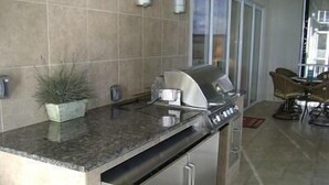 A modern kitchen with a built-in stainless steel range hood, a granite countertop, and a seating area with a table and chairs. - Towers 9106 4 Bedroom Condo by Your Lake vacation (Osage Beach)