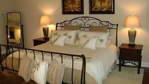 A neatly made bed with a headboard, two bedside tables with lamps, and a mirror on one wall. - Towers 9106 4 Bedroom Condo by Your Lake vacation (Osage Beach)