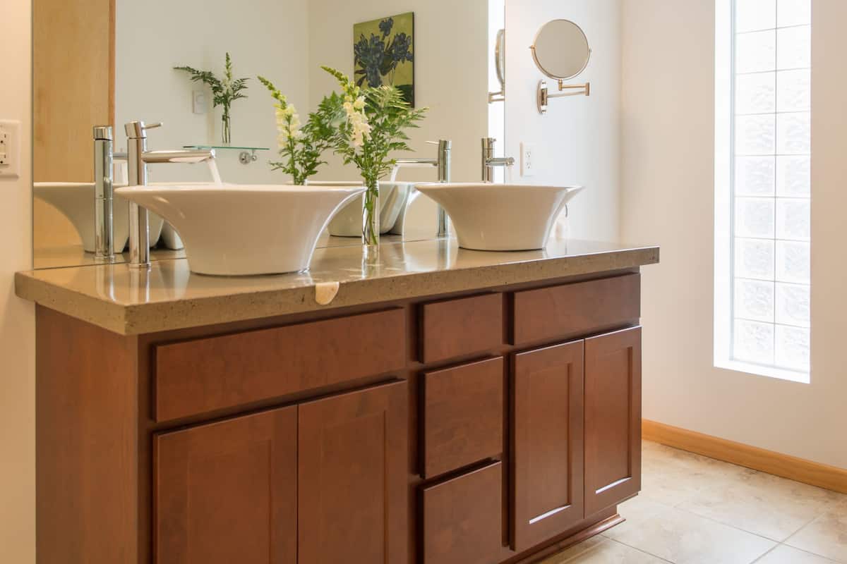 A bathroom with a double sink vanity, a large mirror, and pendant lighting.