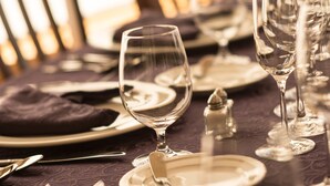 Taula ben a punt per a un sopar formal, amb diversos vasos de vi, plats i coberts.