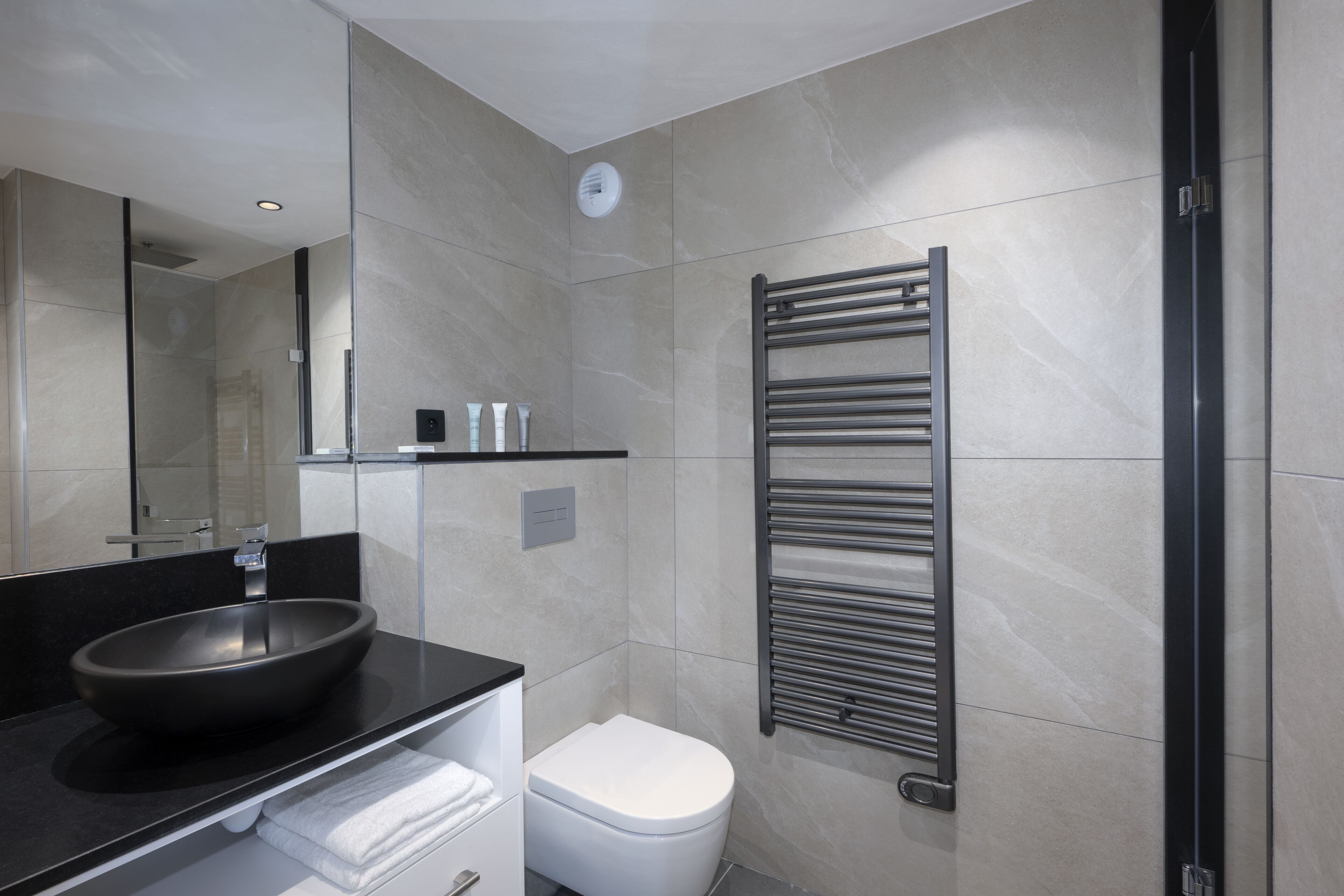 A modern bathroom with a black sink, white toilet, and a towel rack.