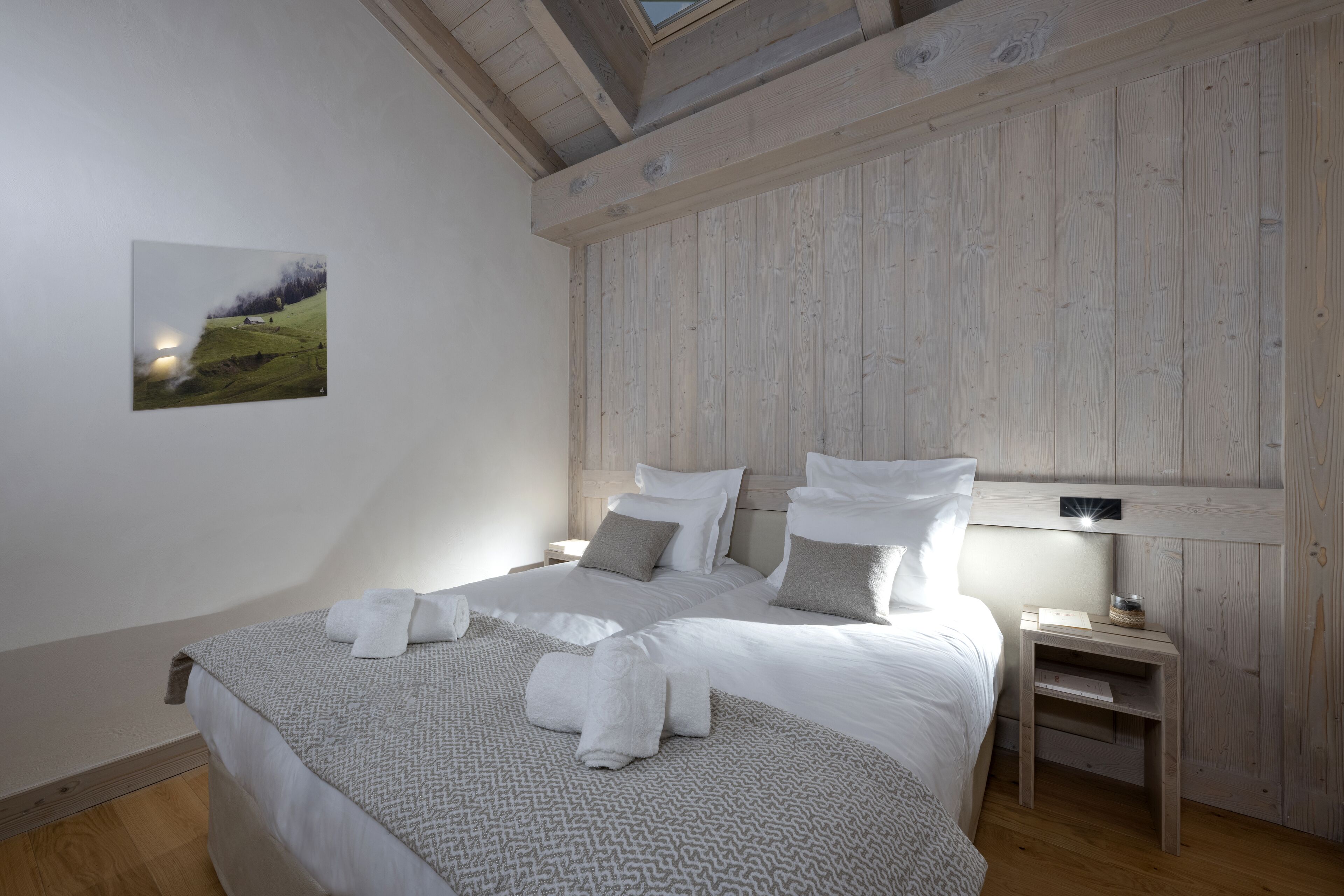 A bedroom with a large bed, two bedside tables, and a wall-mounted light fixture.