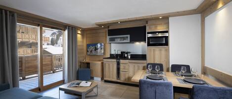 A modern kitchen with wooden cabinets and a dining area with blue chairs.