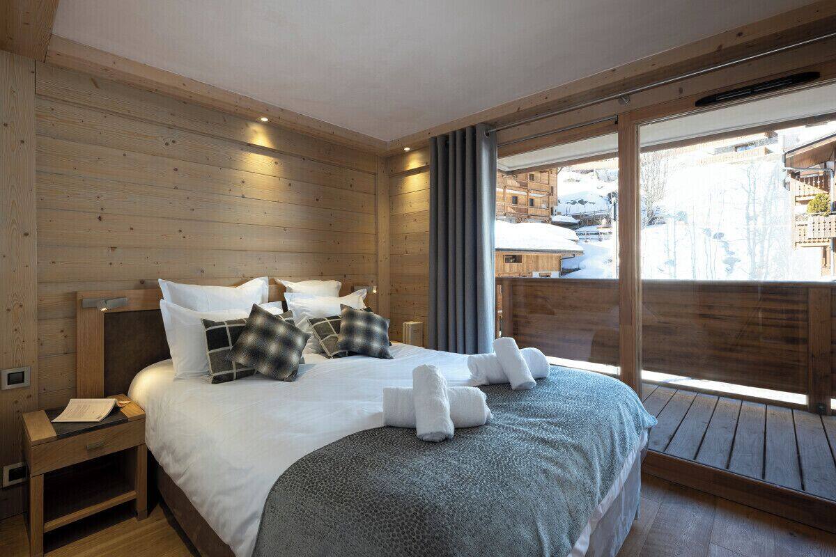 A wooden-paneled room with a bed, a nightstand, and a large window.