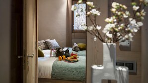 Een gezellige slaapkamer met een bed, kussens, een speeltreinset en een vaas met bloemen.