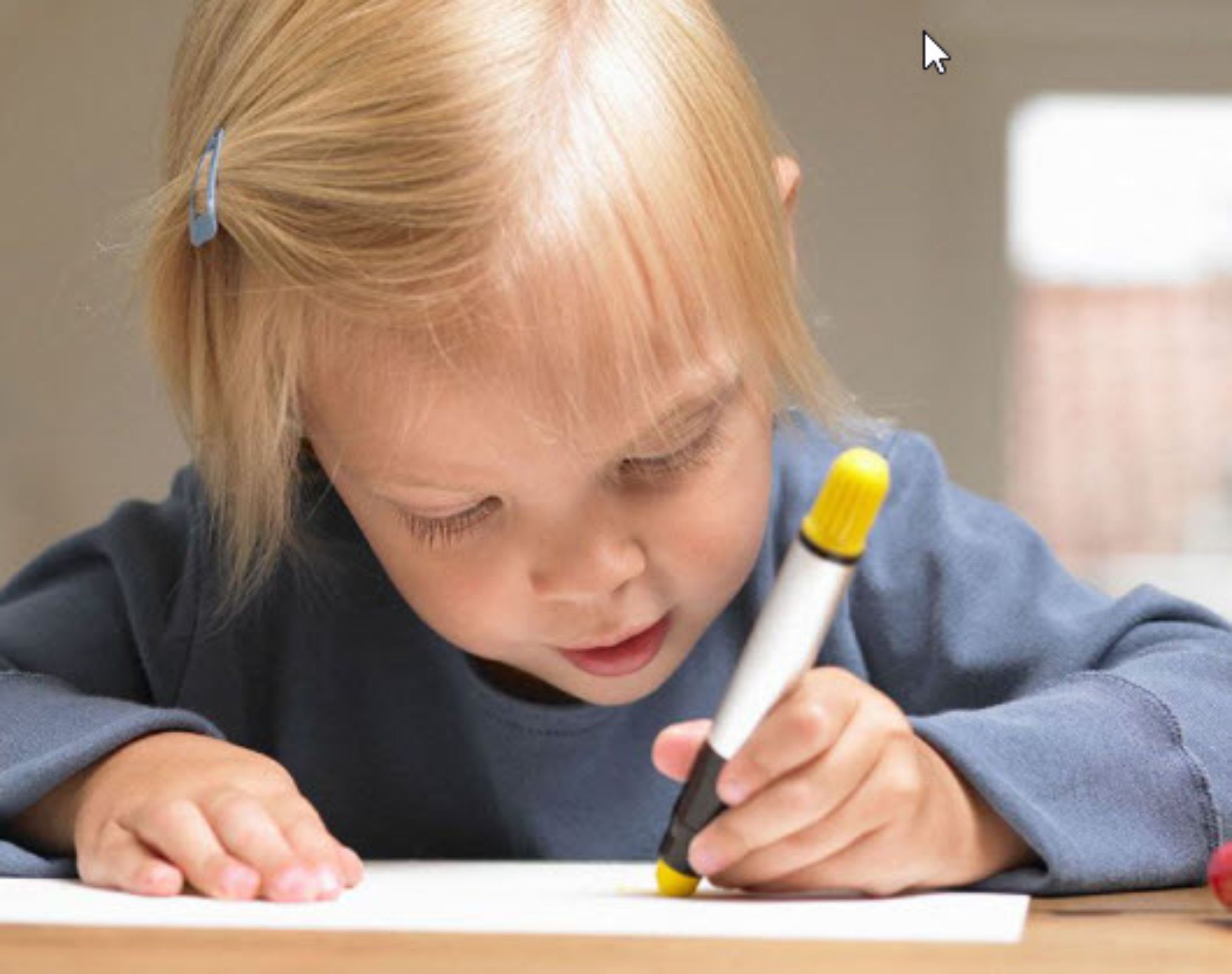 Ein Kind schreibt mit einem gelben Stift auf Papier.