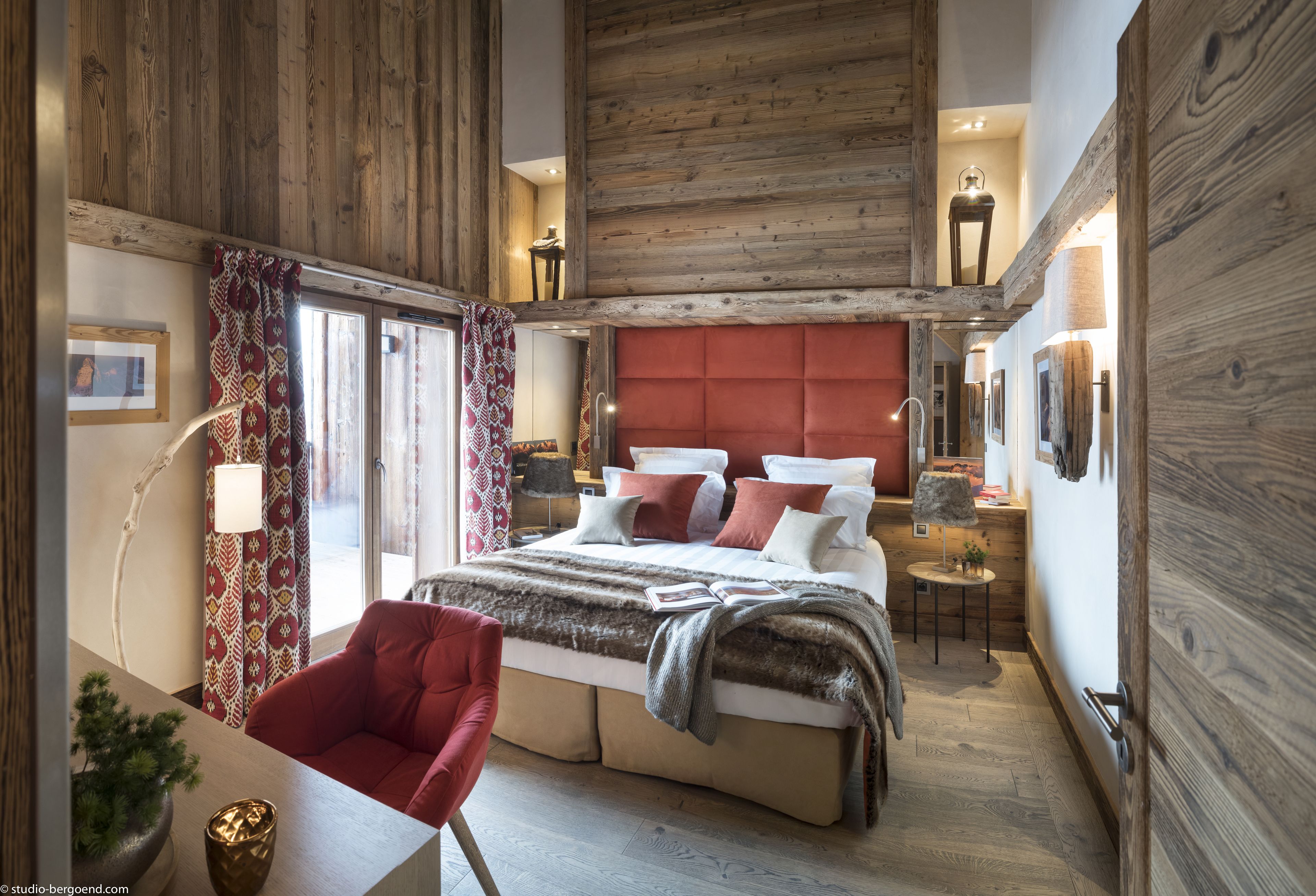 Een slaapkamer met een groot bed, een rode stoel en een houten plafond.