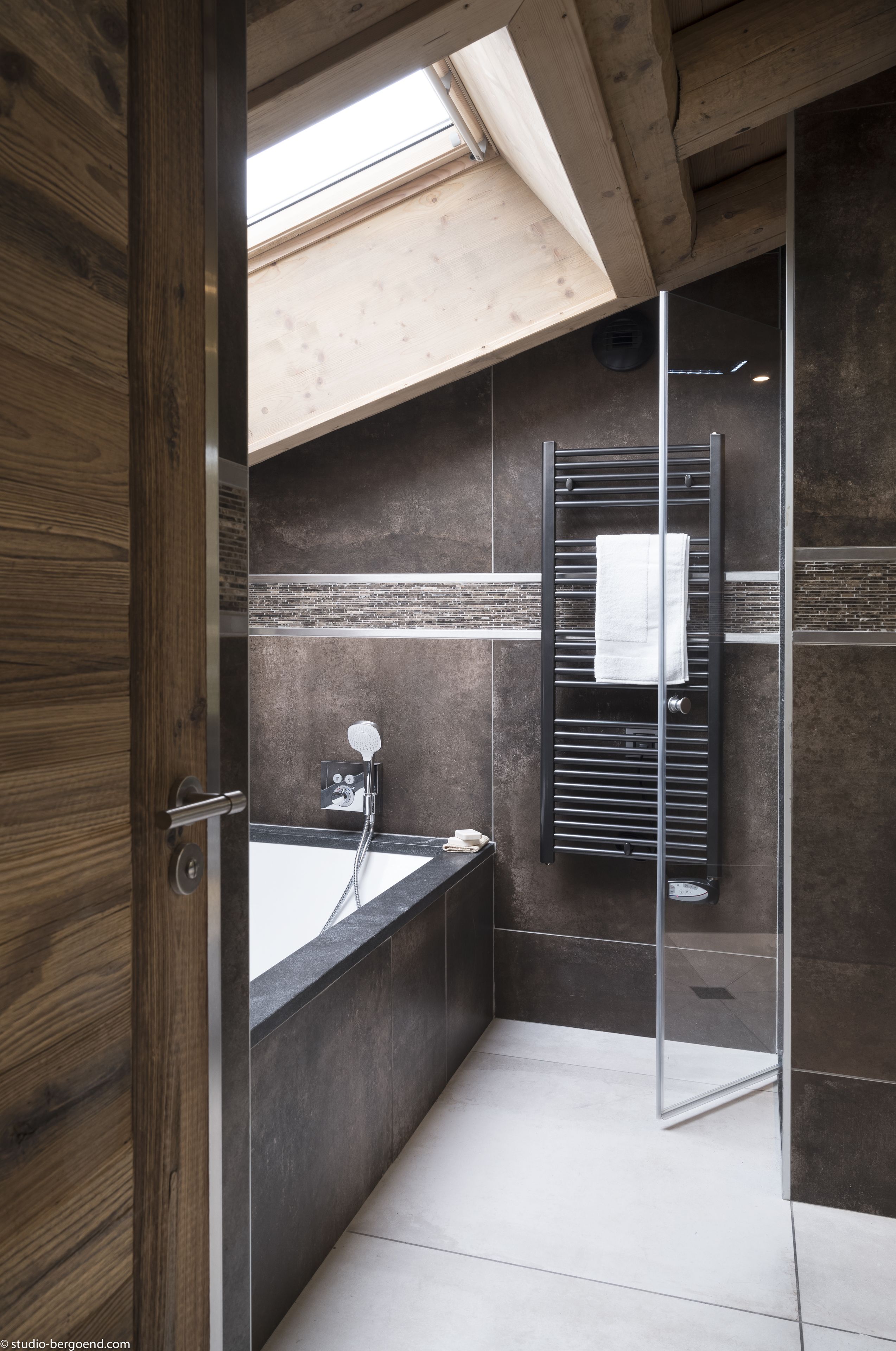 A modern bathroom with a glass shower enclosure, a bathtub, and a towel rack.
