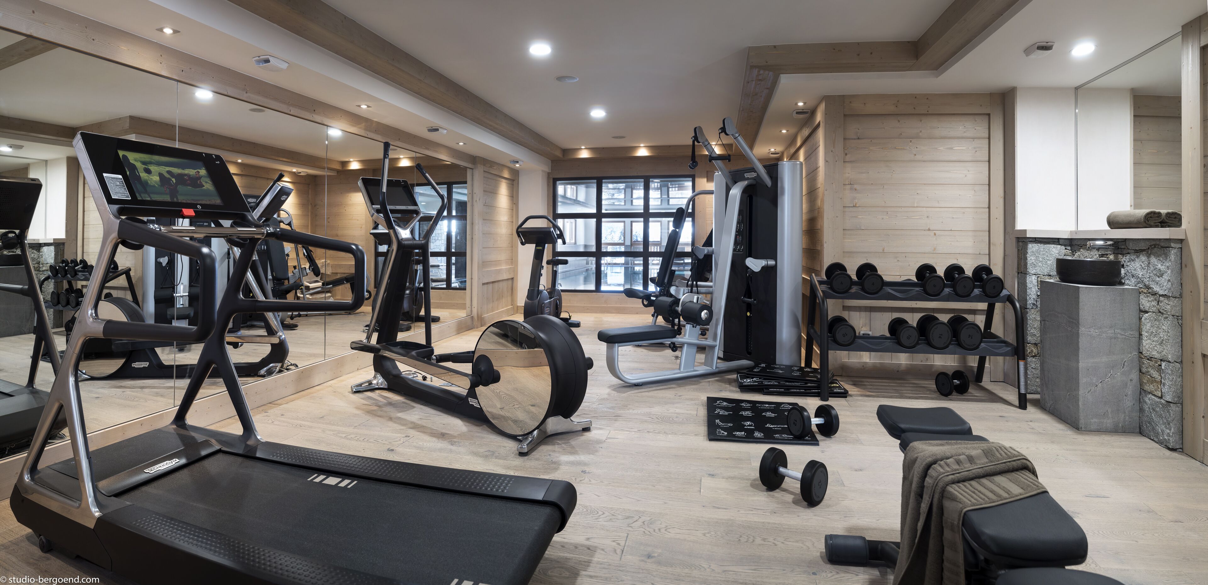 A gym with treadmills, elliptical machines, weight benches, and dumbbells.