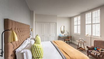 A hotel room with a bed, a desk, a chair, and a window with blinds.
