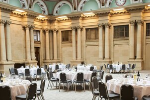 Une salle de banquet avec de nombreuses tables rondes disposées pour le repas, chacune étant agrémentée de chaises et de couverts.