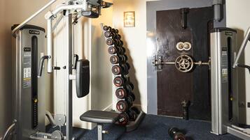 A gym with weightlifting equipment, a bench, and a rack of dumbbells.