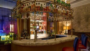 A bar area with a circular bar counter, multiple shelves of bottles, and bar stools. - Harbour Hotel Bristol (Bristol)
