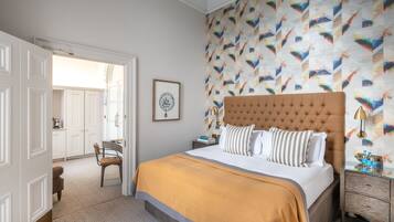 Quarto com cama grande, mesa de cabeceira, cadeira e porta que dá para outro espaço.