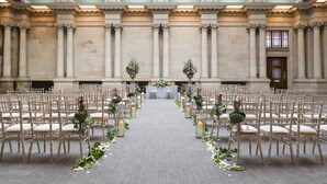 An indoor venue with rows of chairs arranged for an event, a central aisle, and decorative floral arrangements. - Harbour Hotel Bristol (Bristol)
