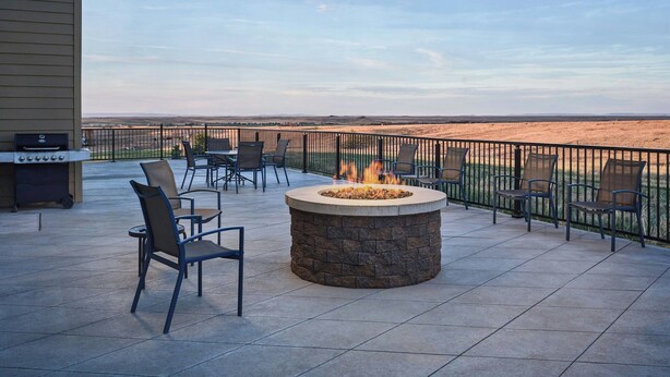 An outdoor patio with a stone fire pit, chairs, and a grill. - Fairfield Inn & Suites by Marriott Sidney (Sidney)