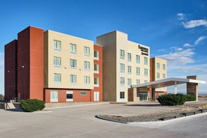 Un hôtel à plusieurs étages, doté d’une façade moderne, d’une entrée couverte et d’un espace paysager à l’avant.