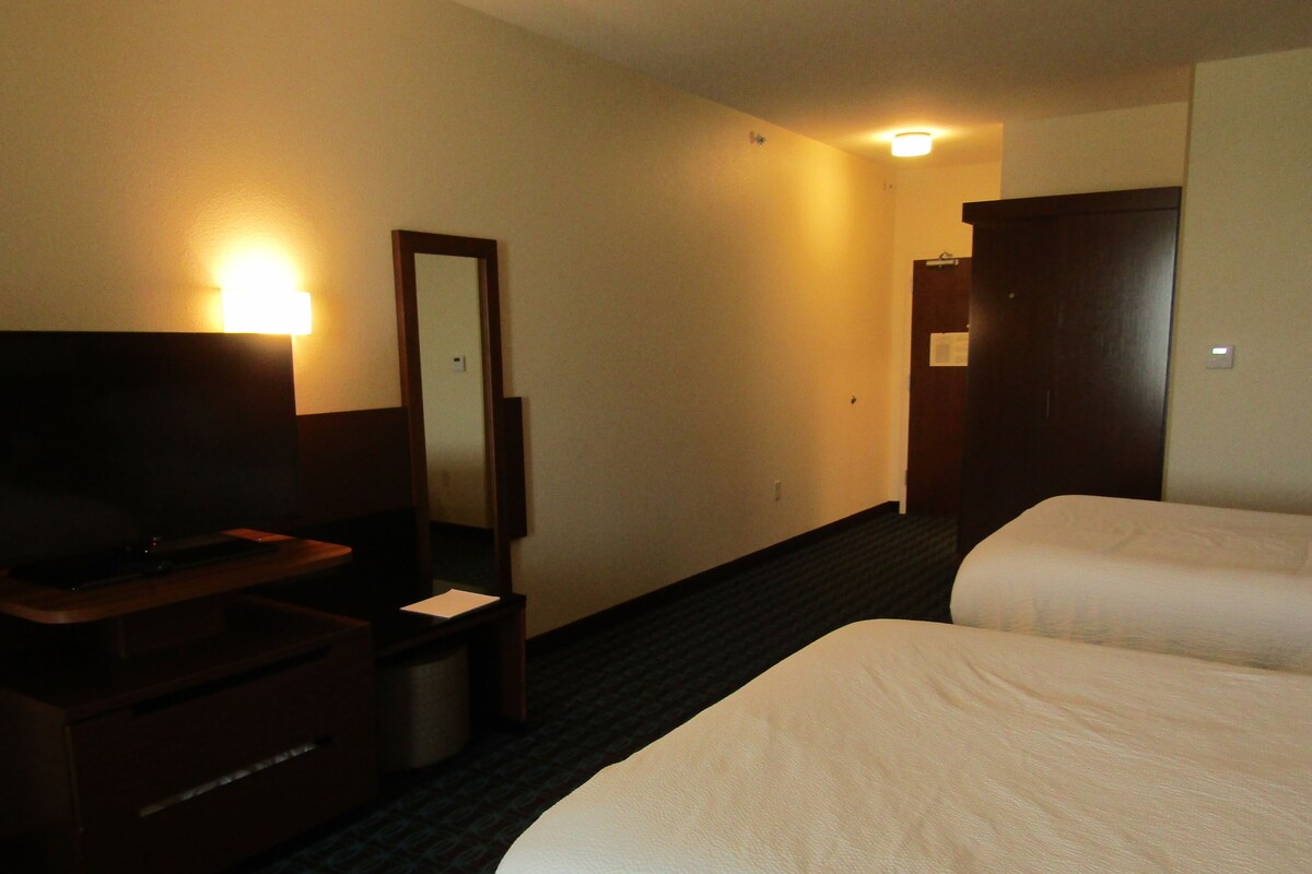 A hotel room with a bed, a TV, a desk, and a mirror.