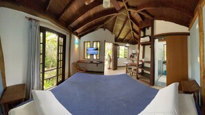 A room with a large bed, wooden beams, a TV, a desk, and a chair. - Casa Jardim Bangalôs (Paraty)