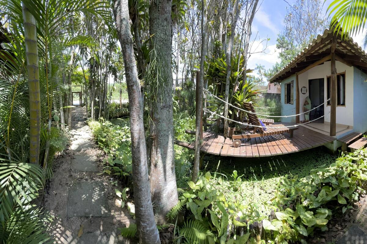 A small, rustic house surrounded by lush greenery and a rope swing.