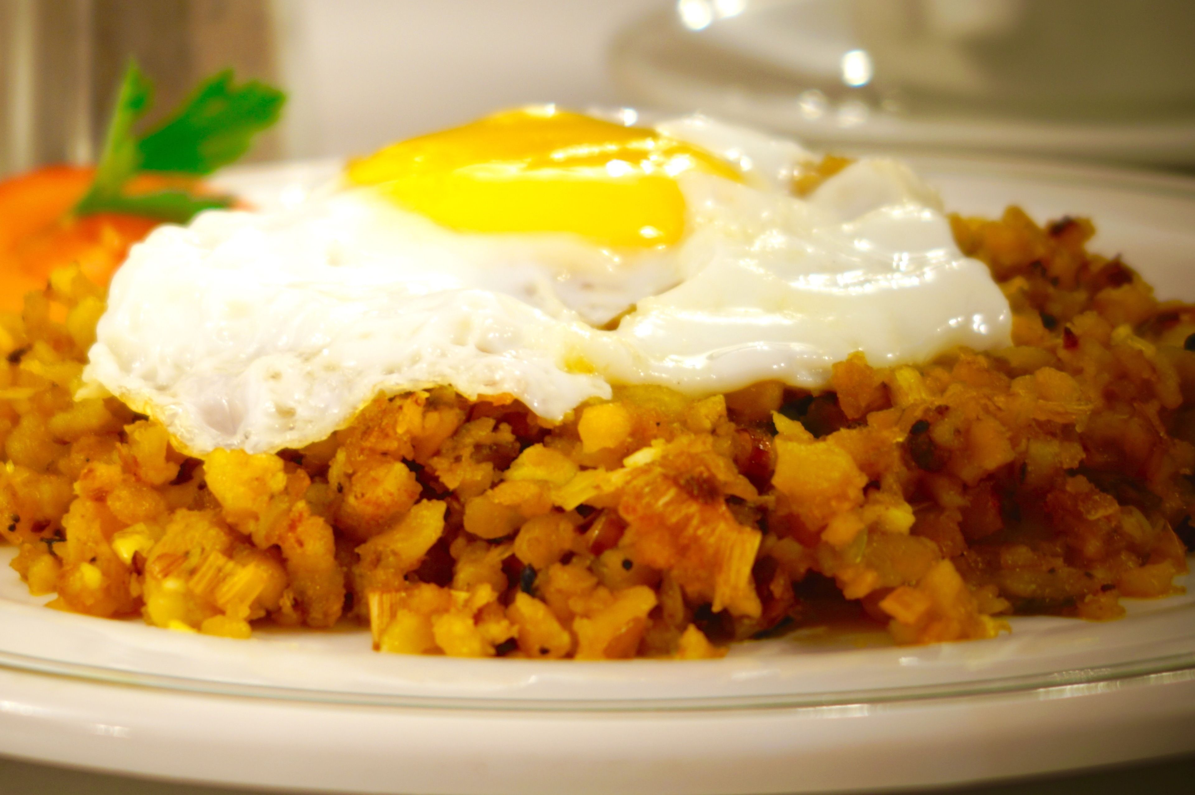A plate of fried rice topped with a fried egg and a garnish of parsley.