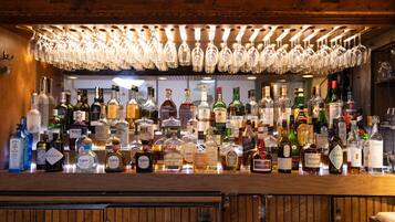 Una zona de bar con mostrador de madera y diversas botellas de licores.