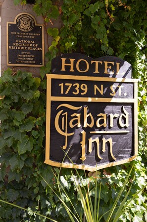 A sign for the Tabard Inn, a historic property listed on the National Register of Historic Places, with ivy and greenery around it.