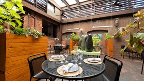 A restaurant with outdoor seating, brick walls, and hanging plants.