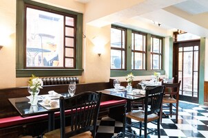 A restaurant with wooden booths and tables, large windows, and a checkered floor.