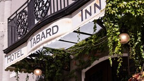 A hotel entrance with a sign reading "HOTEL TABARD INN," surrounded by potted plants and a stone doormat.