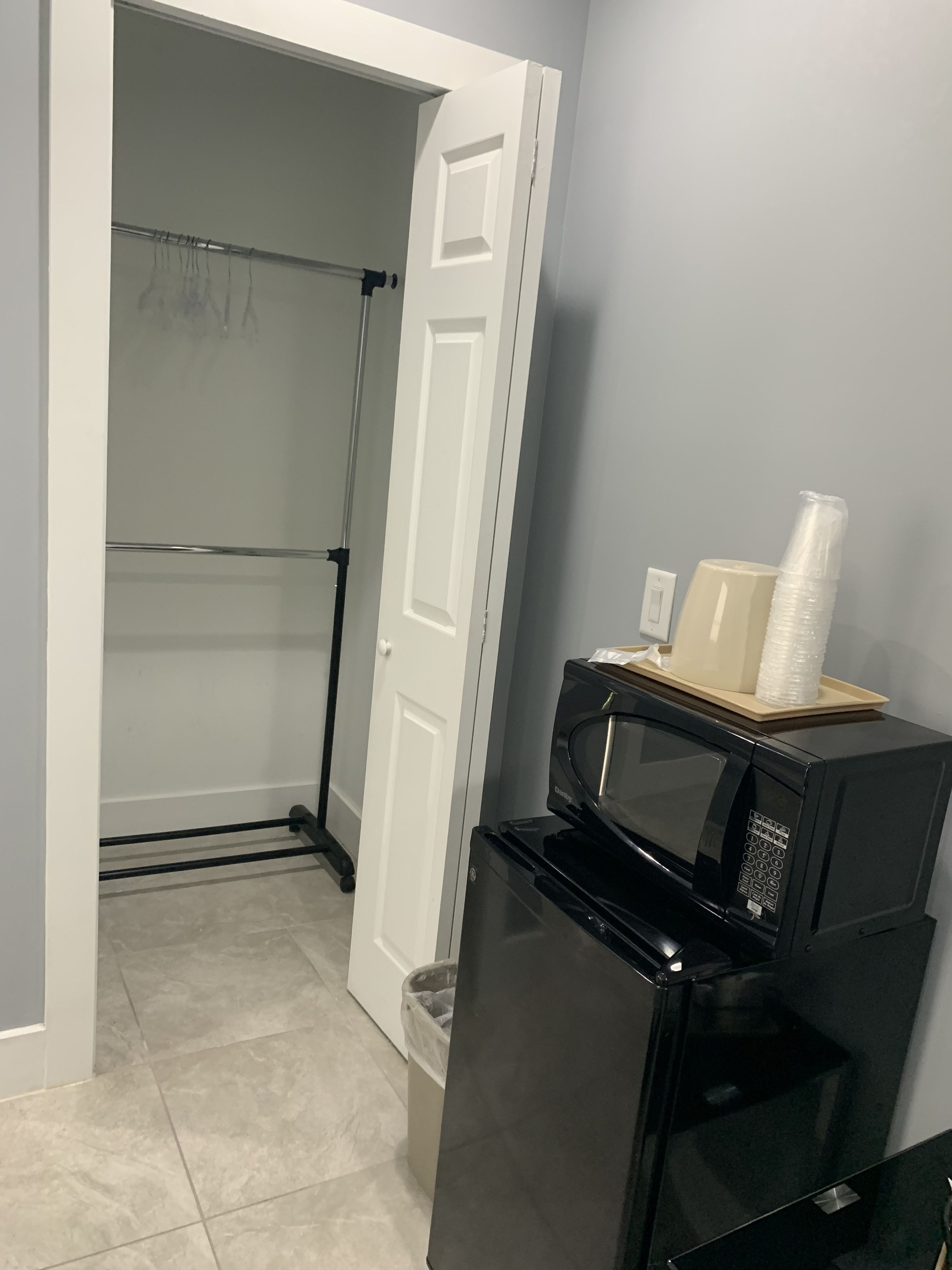 A compact kitchen with a black refrigerator, a microwave, and a small trash bin.