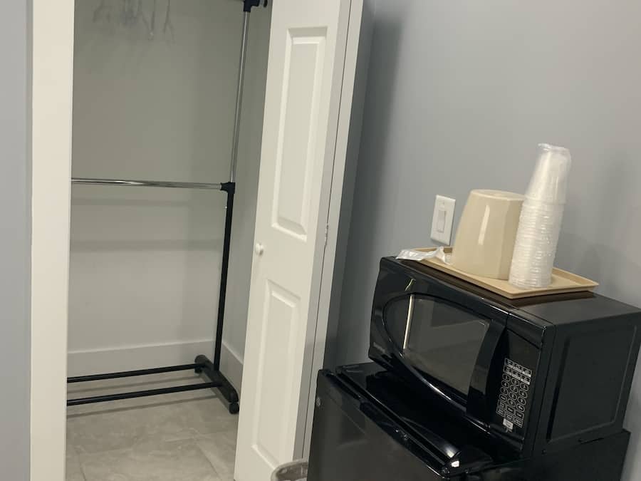 A compact kitchen with a black refrigerator, a microwave, and a small trash bin.