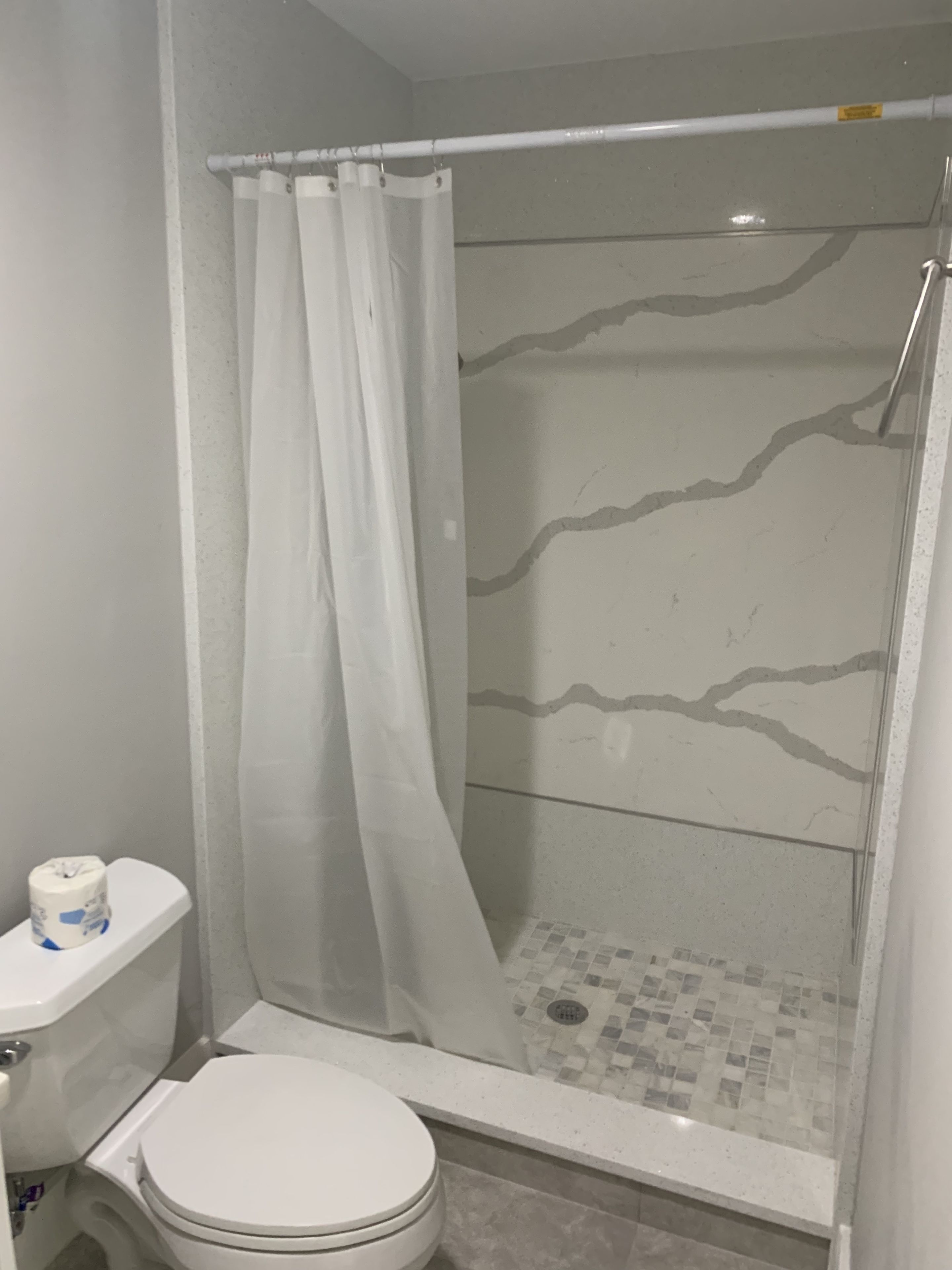 A bathroom with a toilet, shower, and tiled floor.