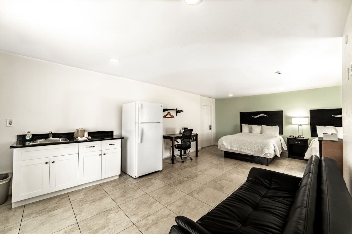 Een compacte hotelkamer met een kitchenette, een bed, een bureau en een bank.