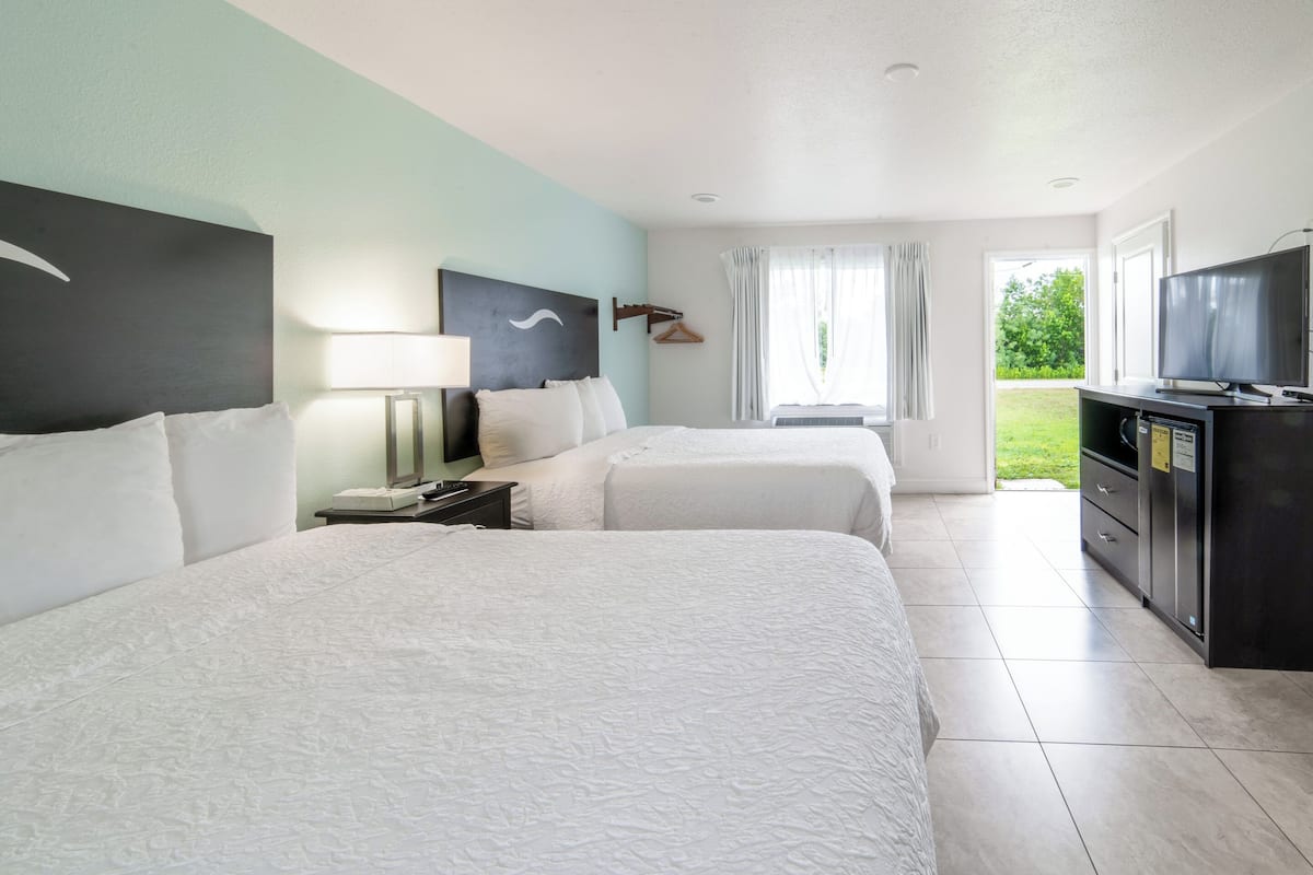 Een hotelkamer met twee bedden, een televisie, een bureau en uitzicht op het omliggende landschap.