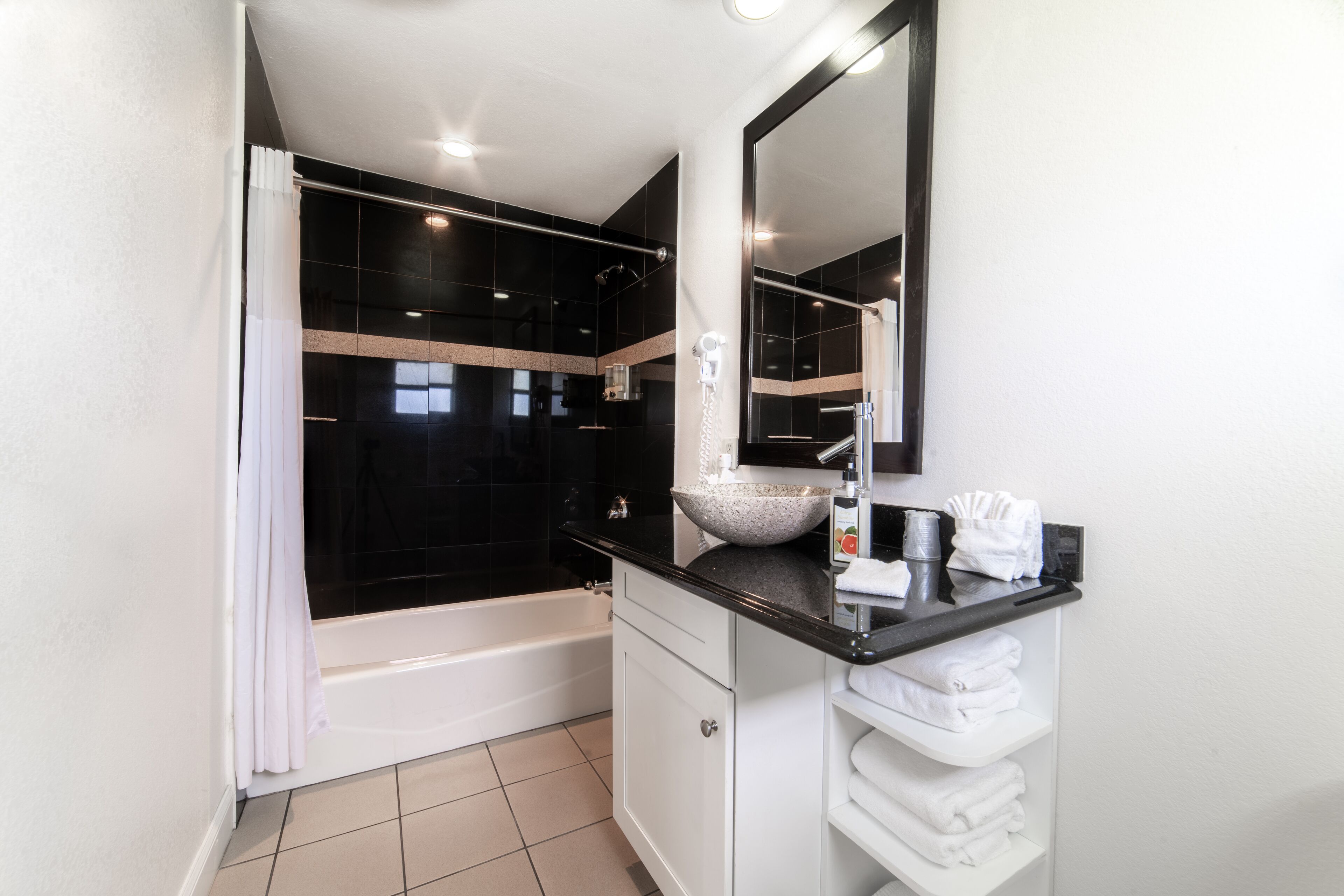 A modern bathroom with a bathtub, a large mirror, a sink with a vessel basin, and a towel rack.