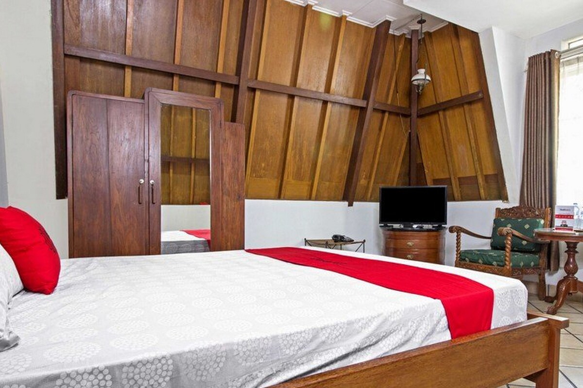 A hotel room with a bed, a television, a desk, and a chair.