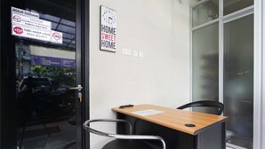 A room with a wooden desk, black office chair, and a wall clock. - RedDoorz @ Mangga Besar 2 (Jakarta)