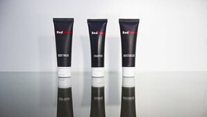 Three RedDoorz body care products: body wash, shampoo, and moisturizer, displayed on a reflective surface. - RedDoorz @ Mangga Besar 2 (Jakarta)