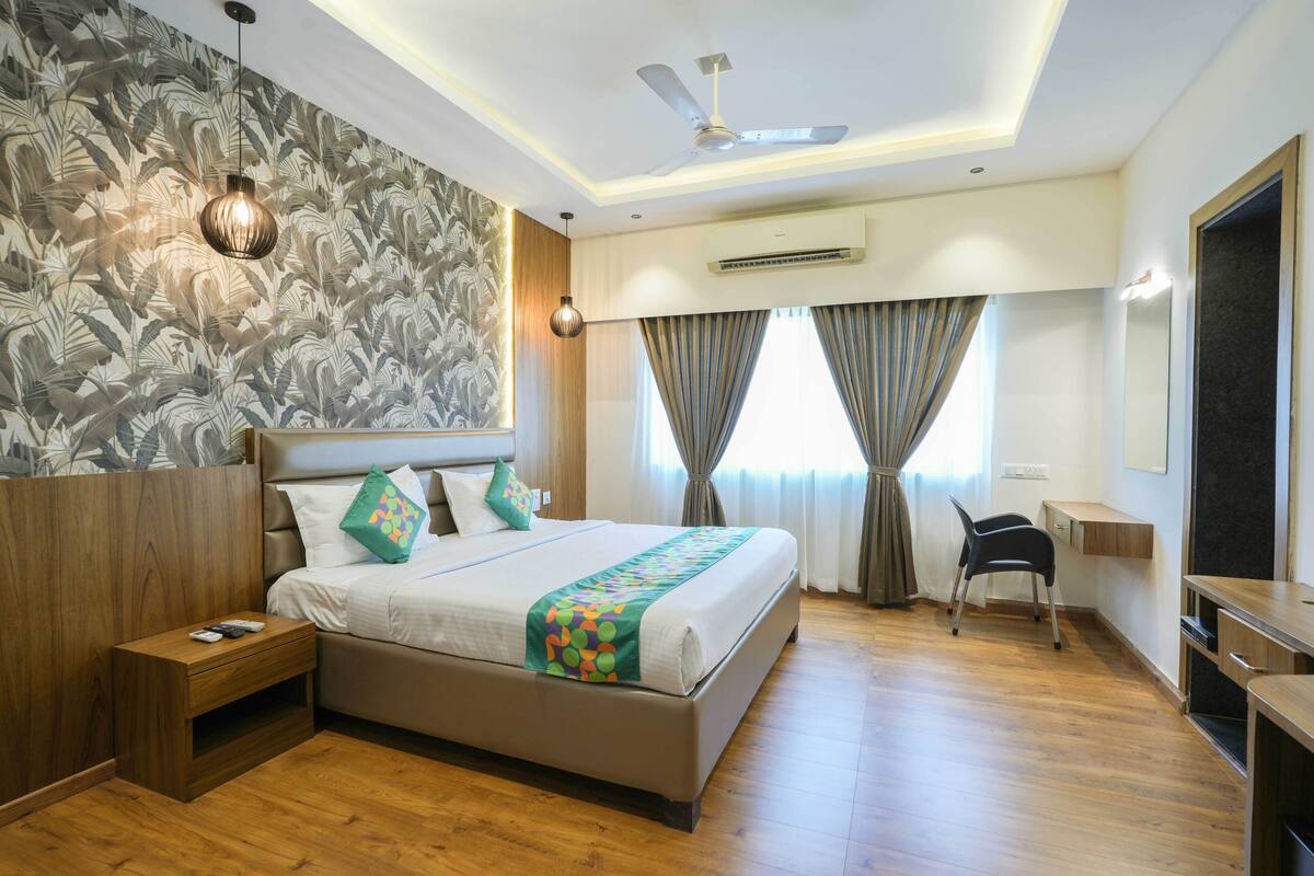 A hotel room with a large bed, a nightstand, a desk, and a chair.