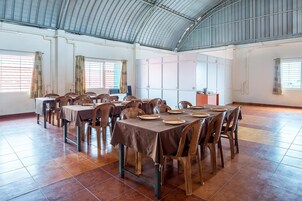 Un comedor espacioso con techos altos, ventanas grandes y suelo de baldosas.