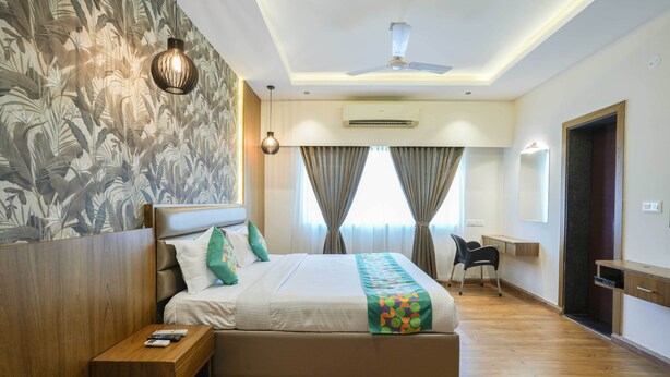 A hotel room with a bed, a desk, a chair, and a ceiling fan. - Treebo Pappilon Palace - PVS Circle (Mangaluru)