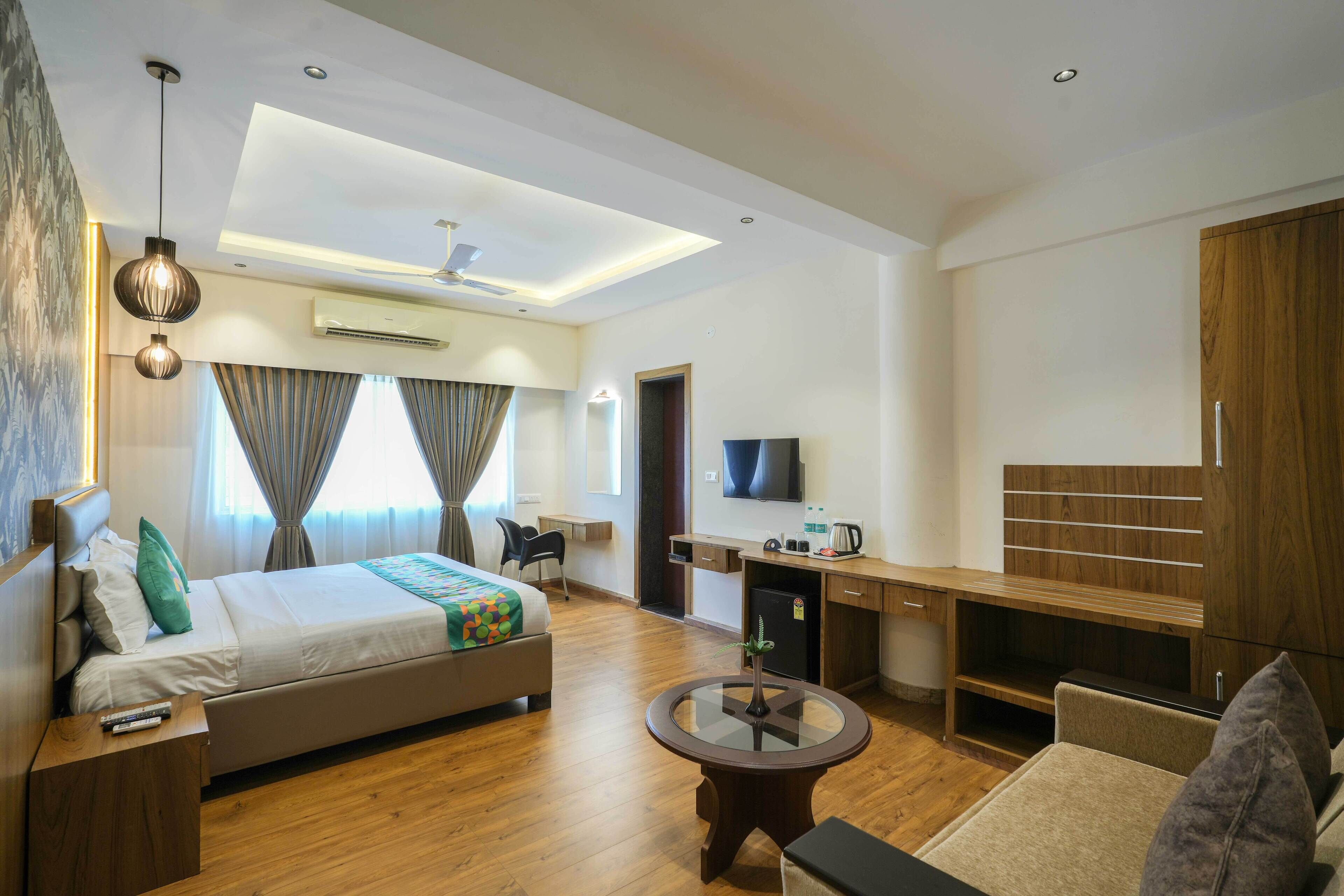 Ein modernes Hotelzimmer mit Bett, Schreibtisch, Fernseher und einer Sitzecke.