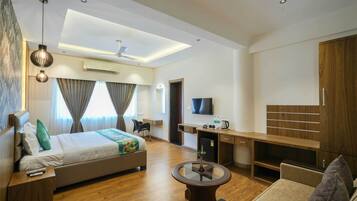 Ein modernes Hotelzimmer mit Bett, Schreibtisch, Fernseher und einer Sitzecke.