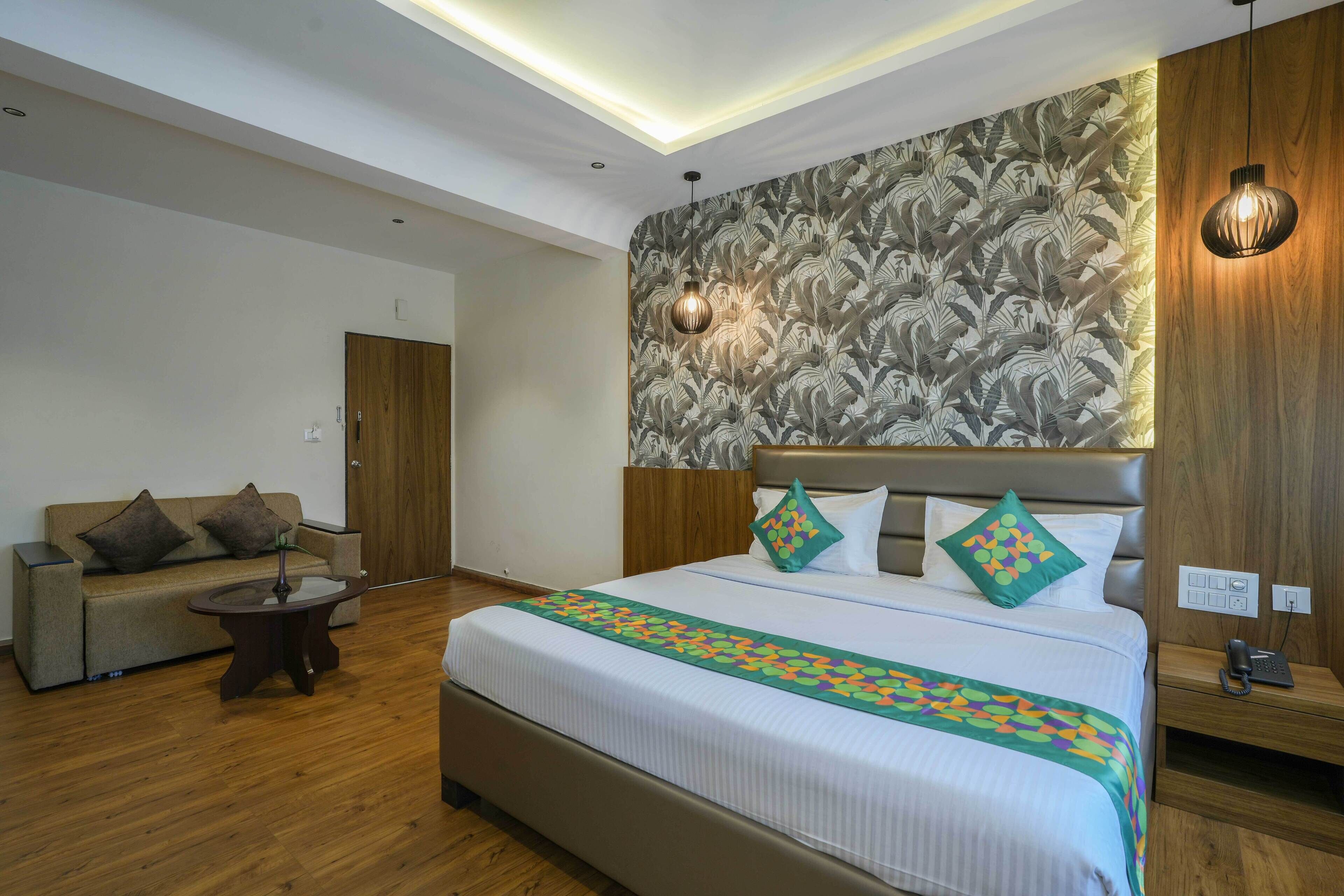 Una habitación de hotel con una cama grande, un sofá, una mesita y un cabecero de madera.