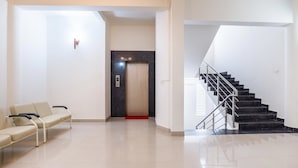 A modern lobby with a waiting area, a staircase, and an elevator. - Treebo Pappilon Palace - PVS Circle (Mangaluru)